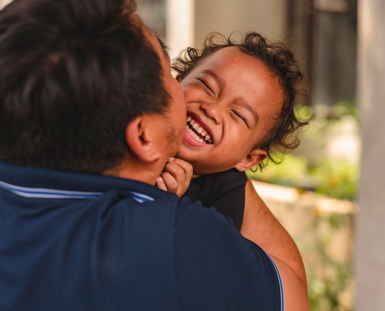 A loving southeast asian man engages in playful bonding with his young son outside their house